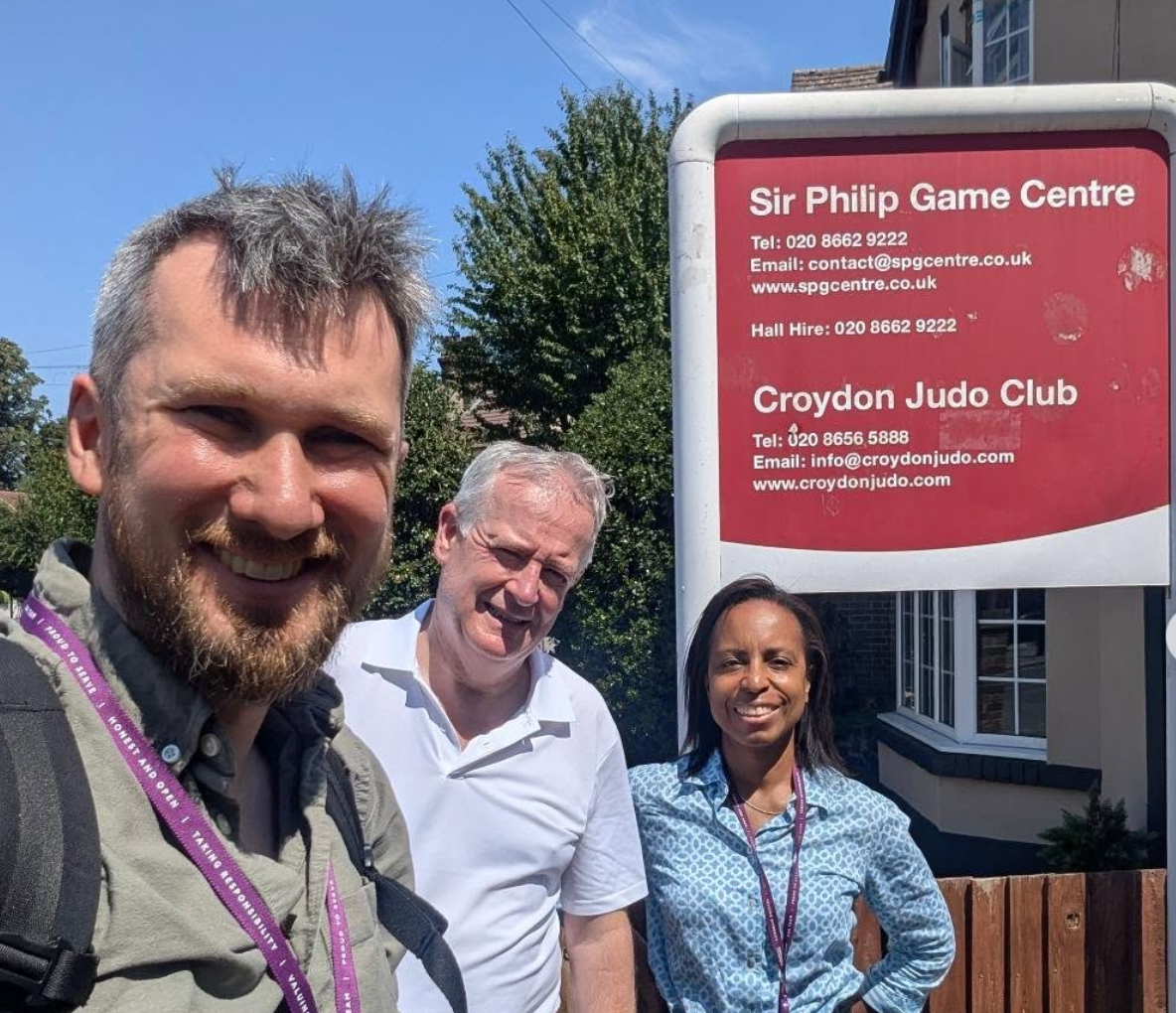 Nick, Sean and Patricia at the Addiscombe West Surgery, July 2026, next to picture of Sir Phillip Game Centre Sign